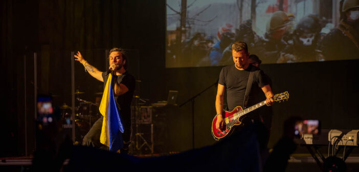 Sergii Tanch and Igor Rybar performing in front of a crowd with a Ukrainian flag