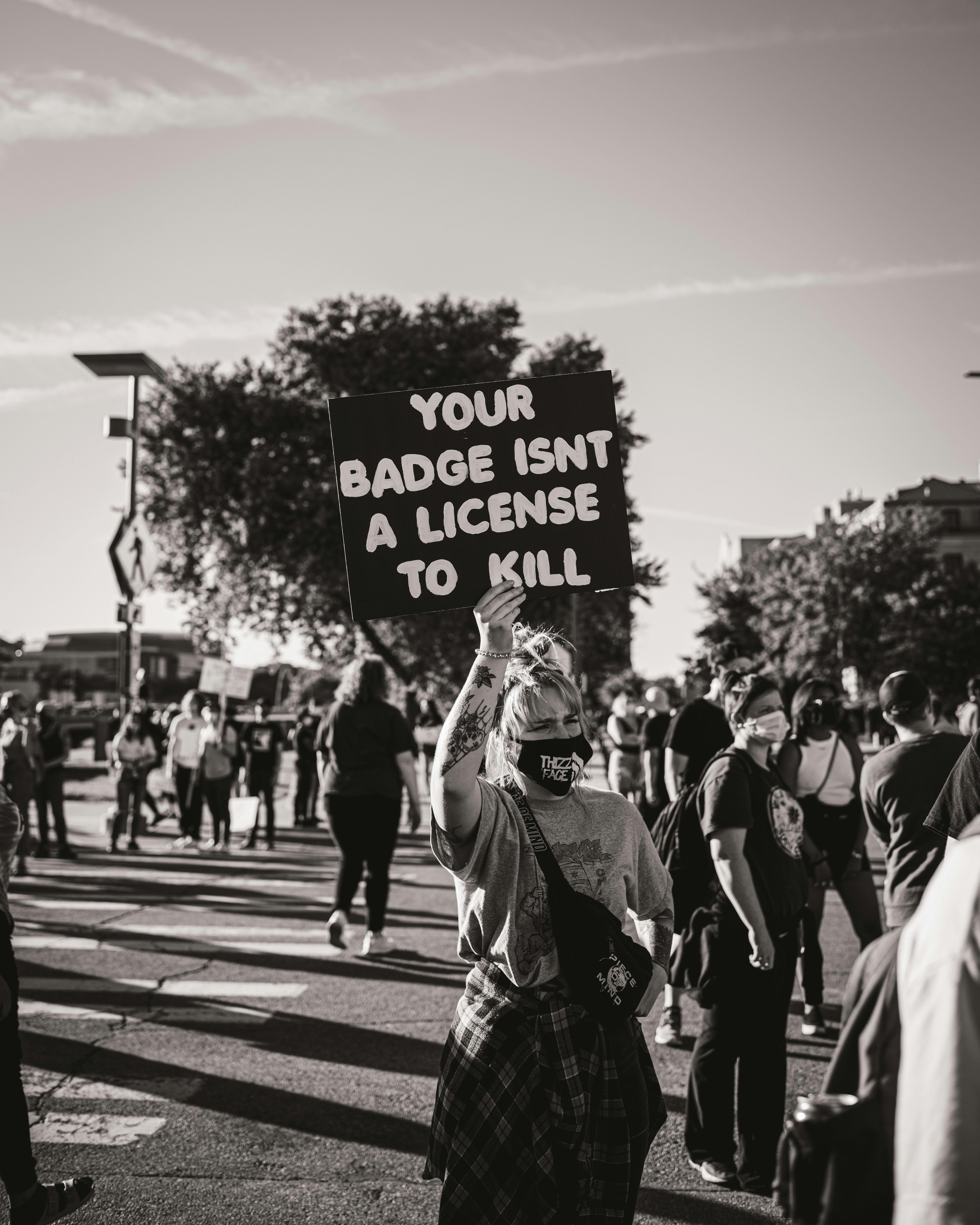Activist holding up protest sign related to police brutality and Sonya Massey.